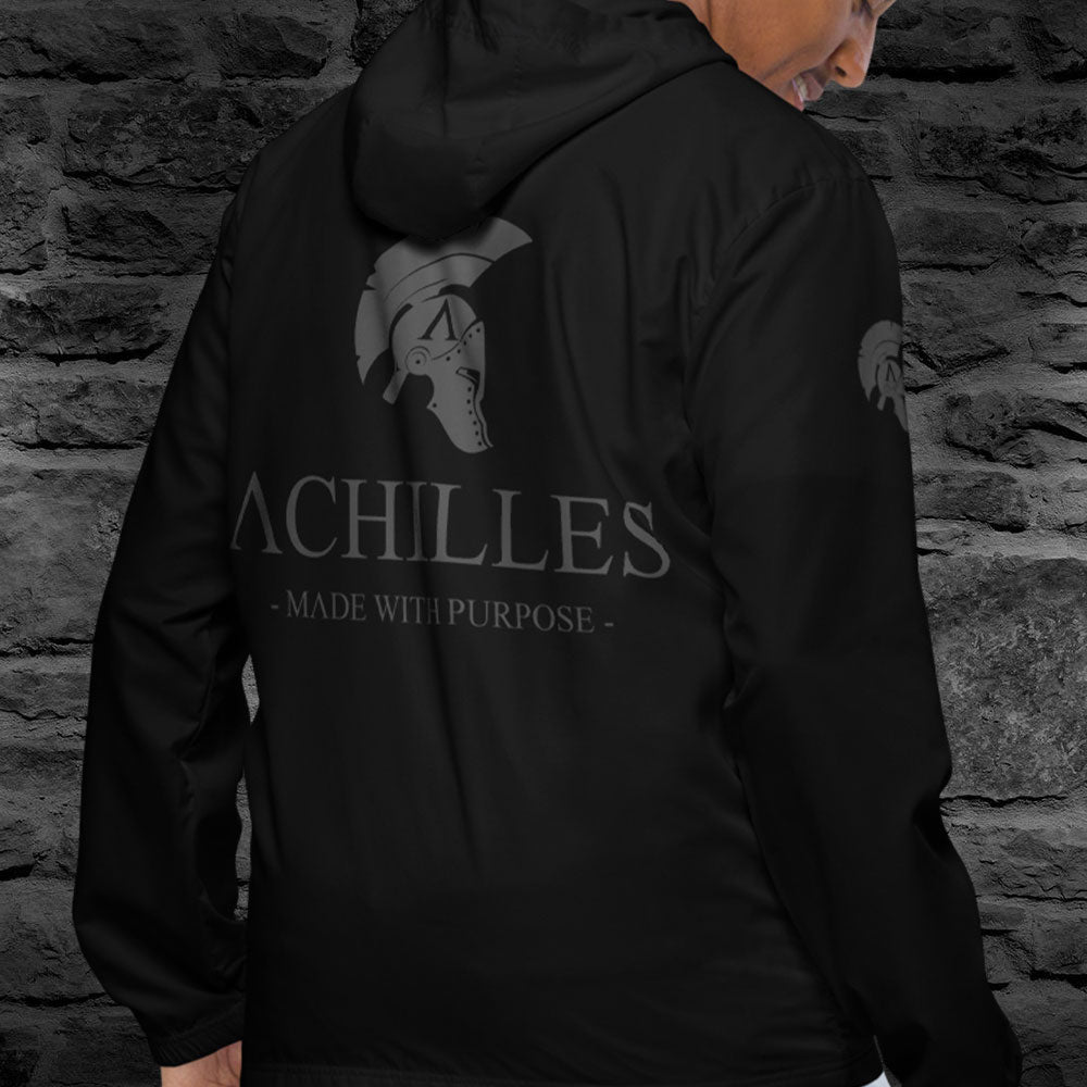 Close up of Back right of man wearing Black long sleeve unisex fit windbreaker jacket by Achilles Tactical Clothing Brand printed with Achilles Signature logo and  helmet design in wolf grey on right sleeves