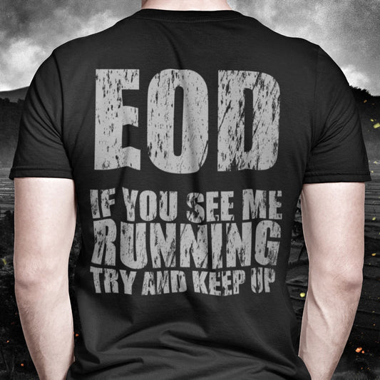 Close up of Front of Man wearing Black short sleeve unisex fit cotton T-Shirt by Achilles Tactical Clothing Brand printed with EOD If You See Me Running Try and Keep Up design across the back