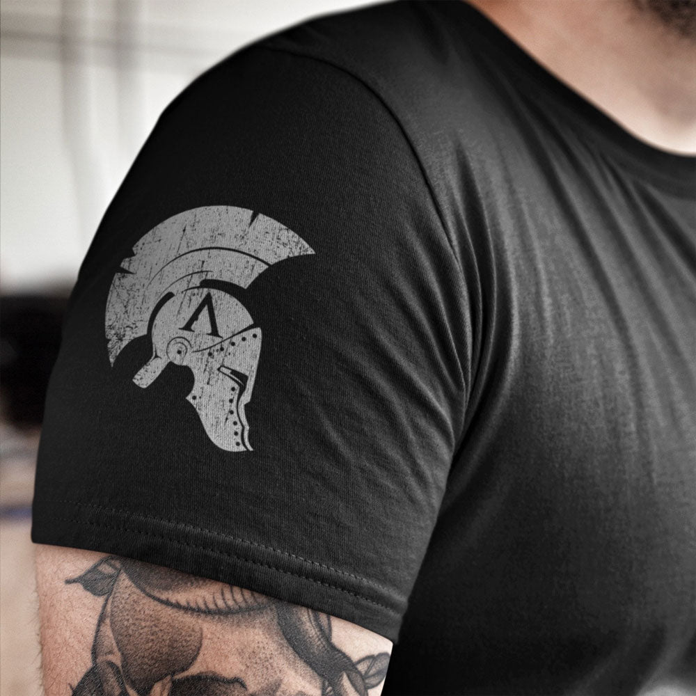 Close up of Distressed achilles helmet logo printed on right sleeve of black cotton short sleeve unisex fit T-Shirt by Achilles Tactical Clothing Brand