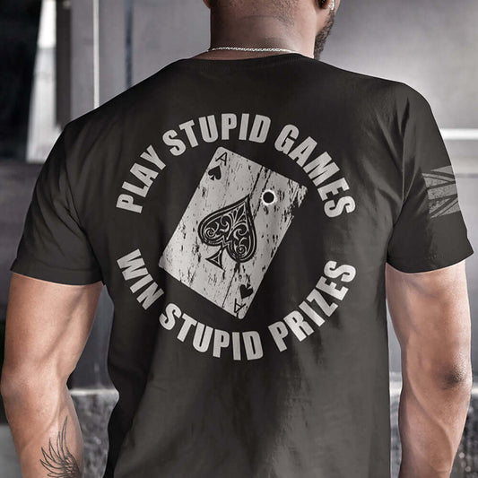 Man wearing Black Short sleeve unisex fit cotton t-shirt designed by Achilles Tactical Clothing brand printed with Play Stupid Games Win Stupid Prizes and the Ace of spades playing with bullet hole across back