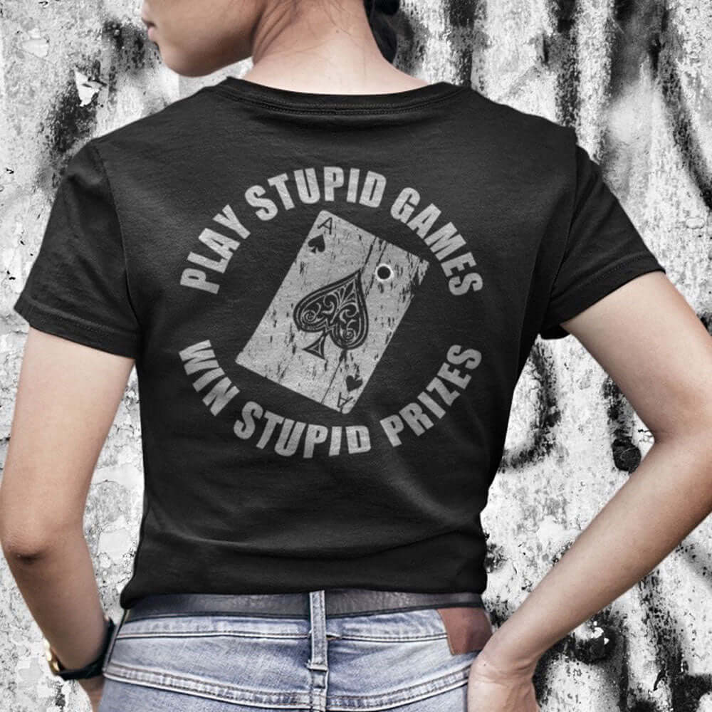 Woman wearing Black Short sleeve unisex fit cotton t-shirt designed by Achilles Tactical Clothing brand printed with Play Stupid Games Win Stupid Prizes and the Ace of spades playing with bullet hole across back